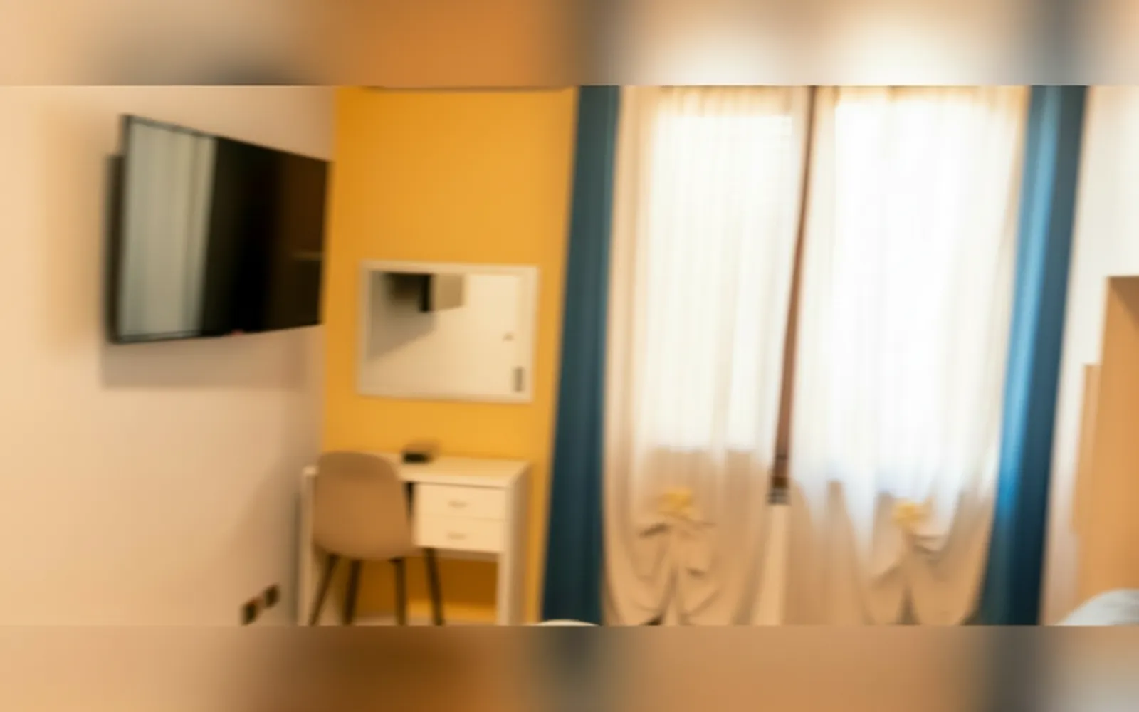 La Camera Matrimoniale Standard con la TV a parete, la scrivania e le tende blu